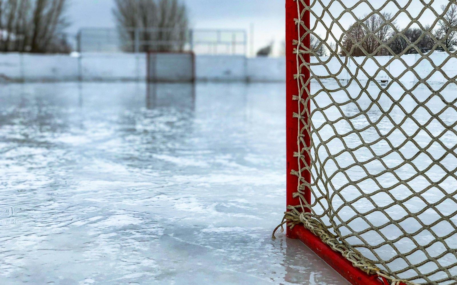 Red and white hockey net on an empty rink